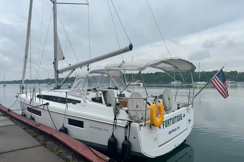 Slide: The Image of Jeanneau Sun Odyssey 410 sailboat docked, displaying American flag, overcast sky. - 2