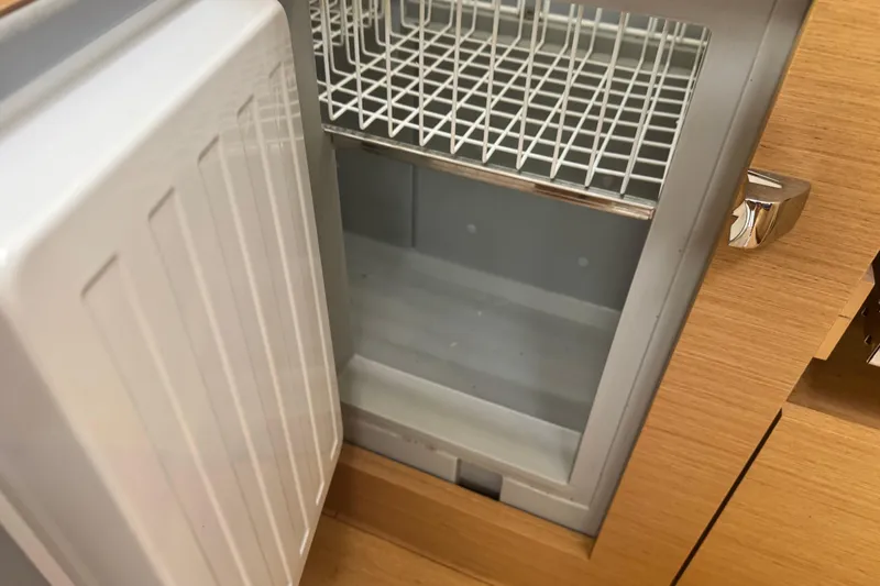 Slide: The Image of Open fridge inside Jeanneau Sun Odyssey 410 yacht, 2020 model, with wooden cabinetry. - 25