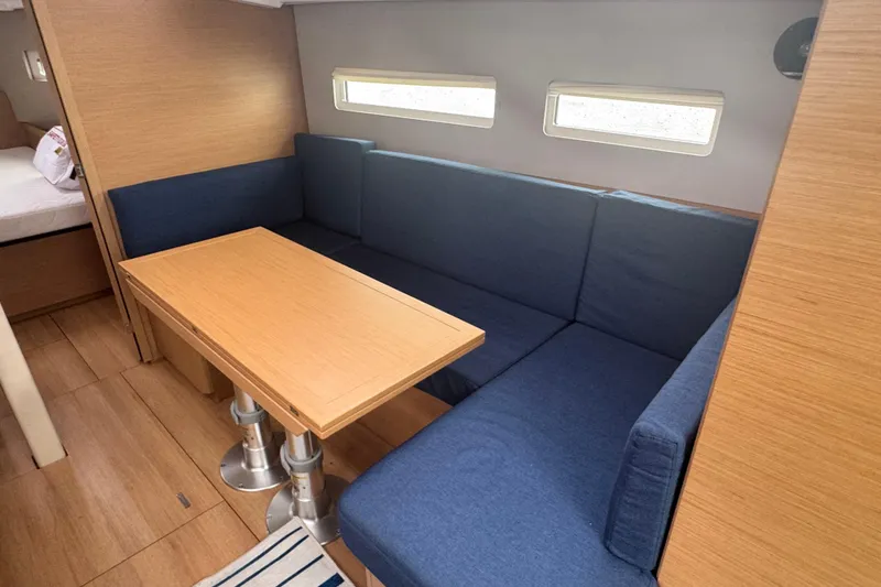 Slide: The Image of Interior of 2020 Jeanneau Sun Odyssey 410 with blue seating and wooden table. - 9