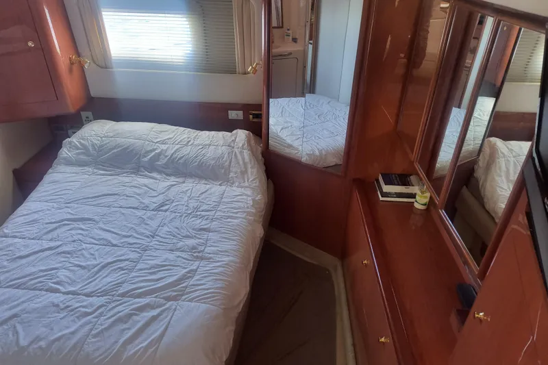 Slide: The Image of 1997 Sea Ray 420 Aft Cabin bedroom with white bedding and wooden cabinetry. - 15