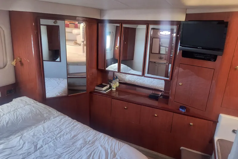 Slide: The Image of Luxurious 1997 Sea Ray 420 Aft Cabin interior with wood cabinetry and cozy bedding. - 16