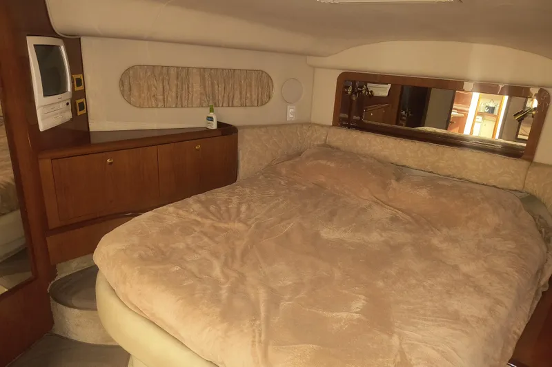 Slide: The Image of 1997 Sea Ray 420 Aft Cabin bedroom with cozy bedding and wooden cabinetry. - 19