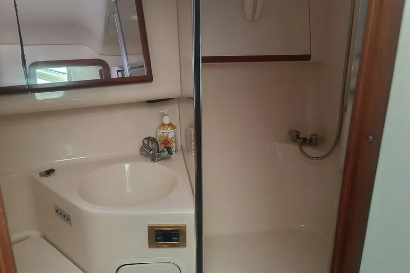 Slide: The Image of 1997 Sea Ray 420 Aft Cabin bathroom with sink, mirror, and shower area. - 21