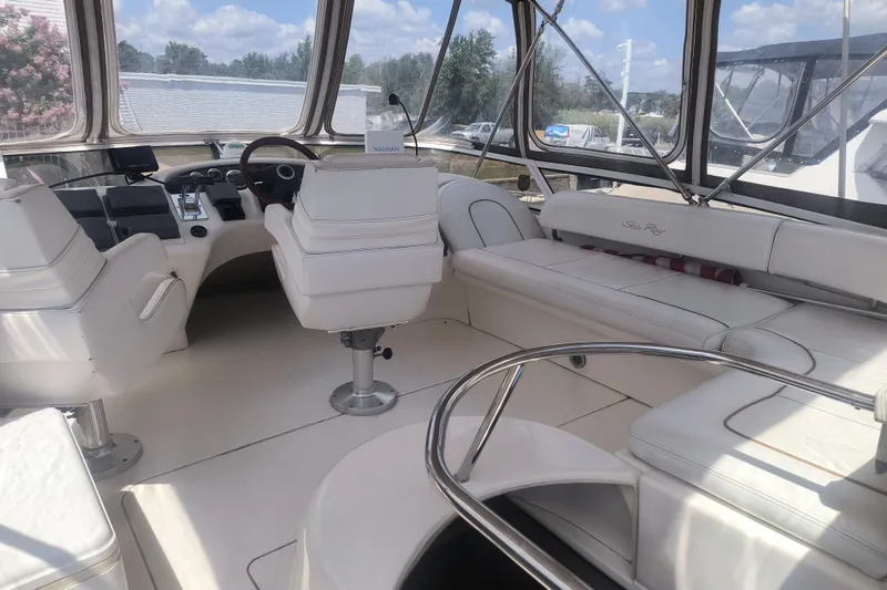 Slide: The Image of 1997 Sea Ray 420 Aft Cabin interior with white seating and helm, sunny day. - 4