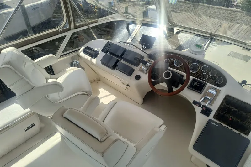 Slide: The Image of 1997 Sea Ray 420 Aft Cabin helm with white seating and wooden steering wheel. - 8