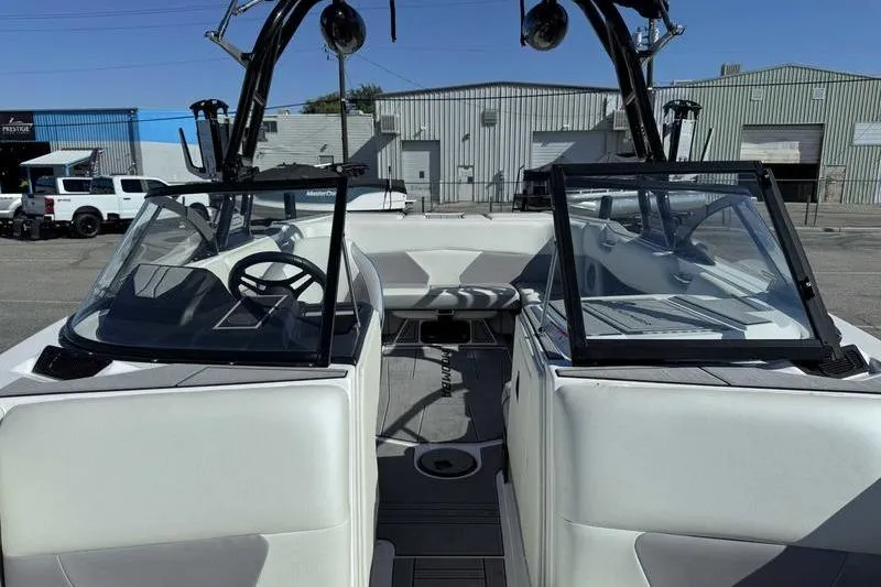 Slide: The Image of 2021 Moomba Max boat interior with open windshield, white seating, and modern dashboard. - 12