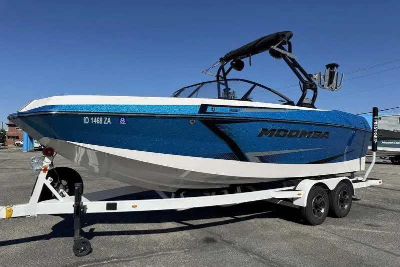 Slide: The Image of 2021 Moomba Max boat on trailer, blue and white design, parked outdoors. - 4
