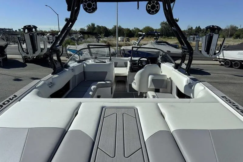 Slide: The Image of 2021 Moomba Max boat interior with seating and steering wheel, parked outdoors. - 7