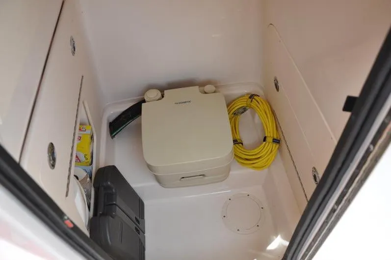Slide: The Image of 2021 Grady-White Fisherman 236 storage area with portable toilet and yellow hose. - 28