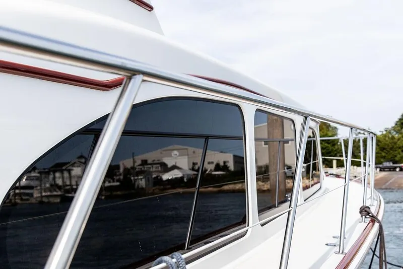 Slide: The Image of 2008 Huckins Linwood yacht with sleek design and reflective windows docked by the shore. - 13