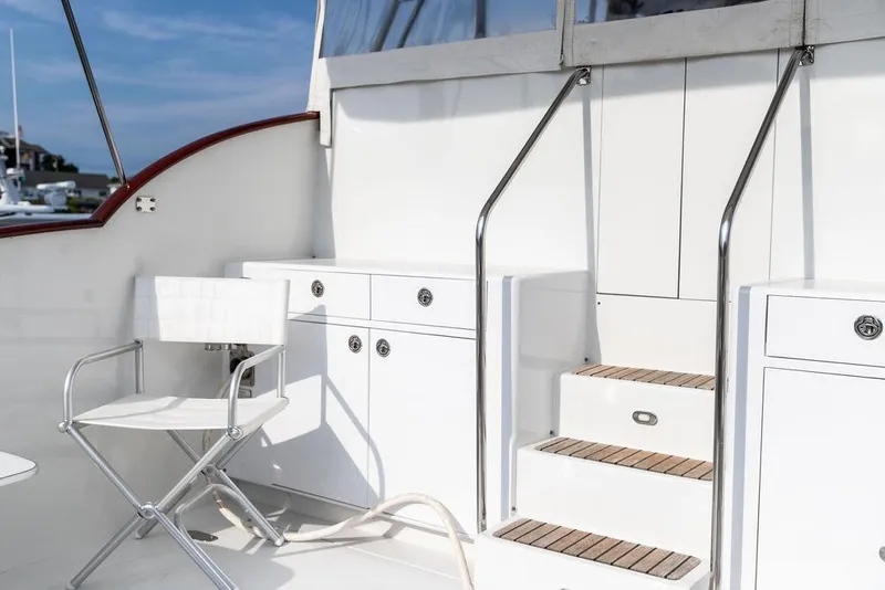 Slide: The Image of 2008 Huckins Linwood yacht deck with white chair, cabinets, and wooden steps. - 17