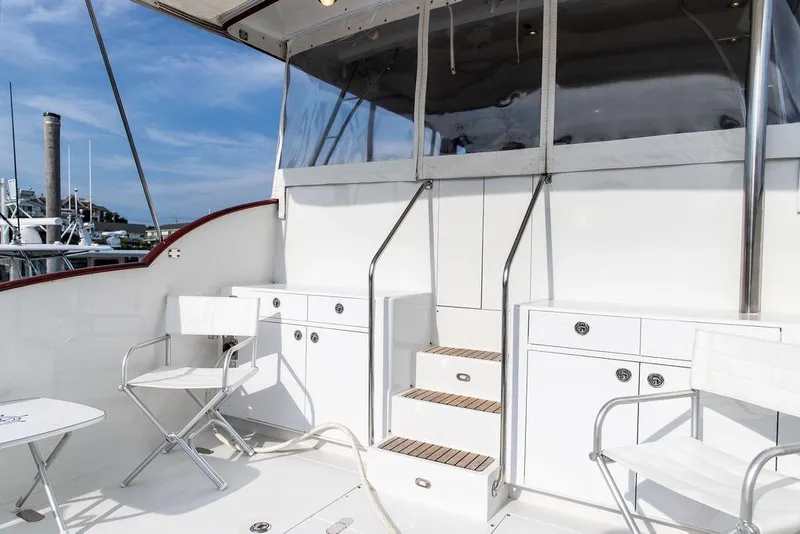 Slide: The Image of 2008 Huckins Linwood yacht deck with white chairs and cabinetry under a clear sky. - 41