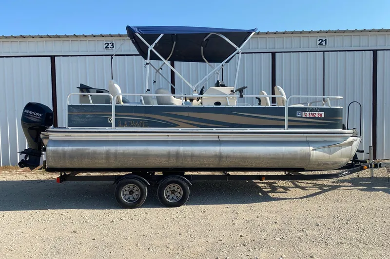 The Image of 2014 Lowe SF214 Sport Fish pontoon boat on trailer, parked outdoors. - 0