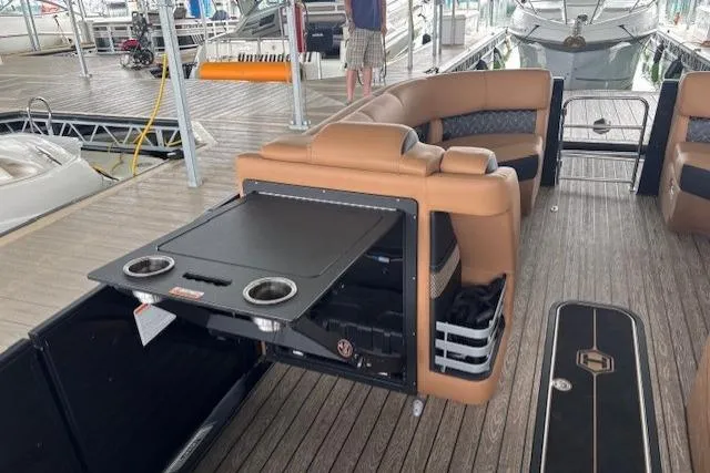 Slide: The Image of 2025 Harris Grand Mariner 230 interior with seating and fold-out table on a docked boat. - 9