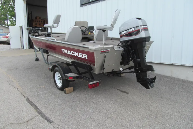Slide: The Image of 1998 Tracker boat with outboard motor on trailer, parked near a building. - 3
