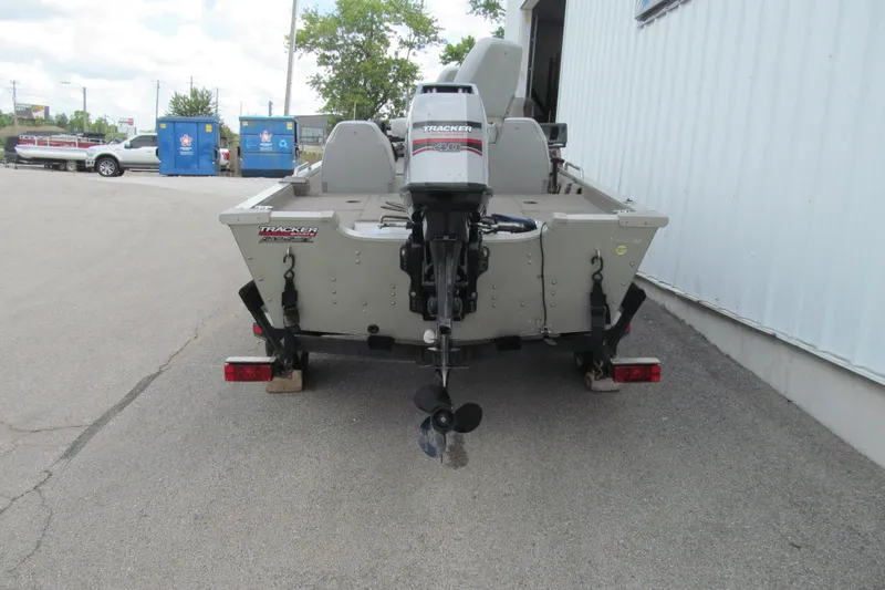 Slide: The Image of 1998 Tracker boat with outboard motor on trailer, parked near a building. - 4