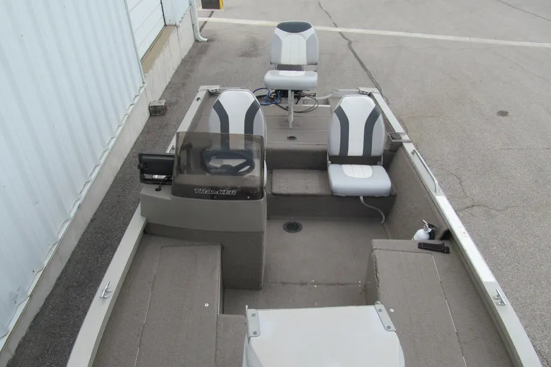 Slide: The Image of 1998 Tracker boat interior with steering console and two seats on a concrete surface. - 9