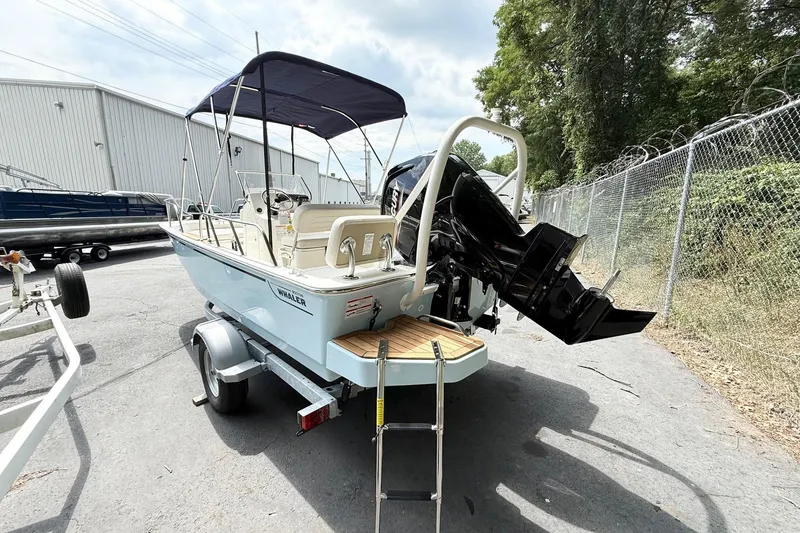 Slide: The Image of 2026 Boston Whaler 170 Montauk boat on trailer, parked outdoors near a fence. - 1