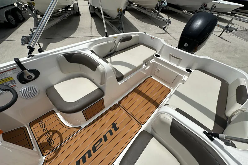 Slide: The Image of 2021 Bayliner Element E18 boat interior with cushioned seating and wood-style flooring. - 11