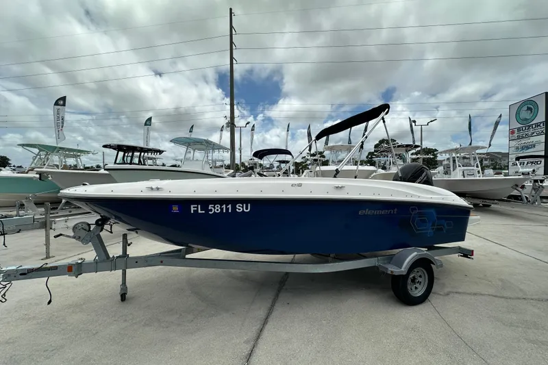 Slide: The Image of 2021 Bayliner Element E18 boat on trailer at dealership, cloudy sky background. - 2