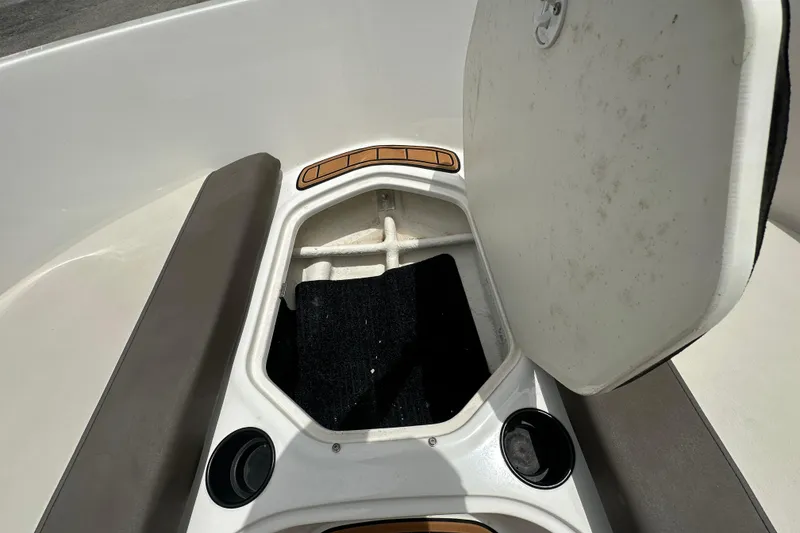 Slide: The Image of 2021 Bayliner Element E18 boat storage compartment with open hatch and cup holders. - 6