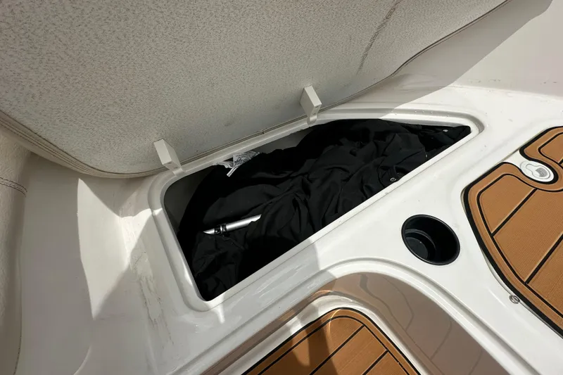 Slide: The Image of 2021 Bayliner Element E18 boat storage compartment with black items inside. - 8