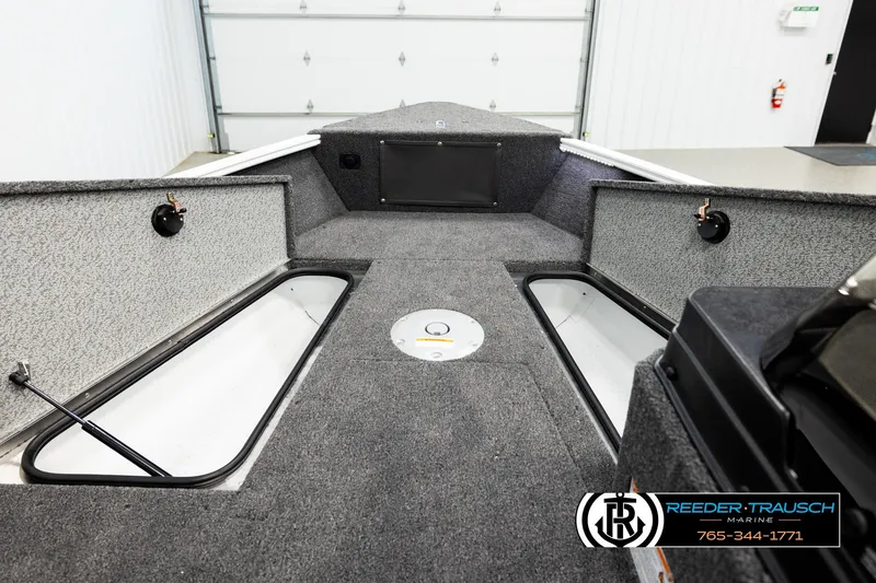 Slide: The Image of 2026 Lund 1775 Adventure SS boat interior with storage compartments and carpeted deck. - 14