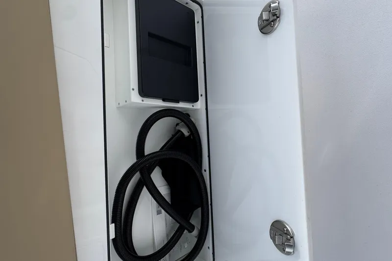 Slide: The Image of 2026 Sportsman Heritage 321 Center Console storage compartment with coiled hose and secure latches. - 12