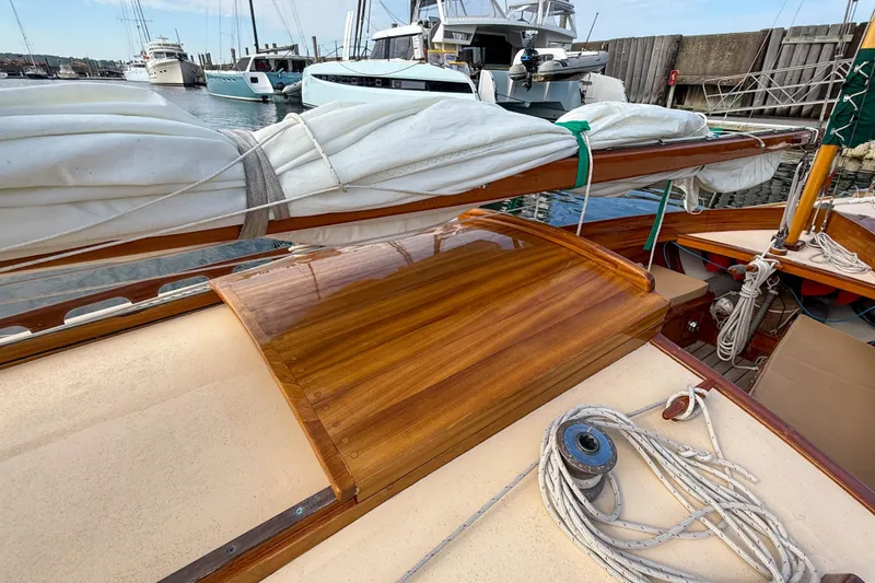 Slide: The Image of 2012 Herreshoff Custom Hyland Design "Rozinante" sailboat with wooden deck and coiled ropes. - 27