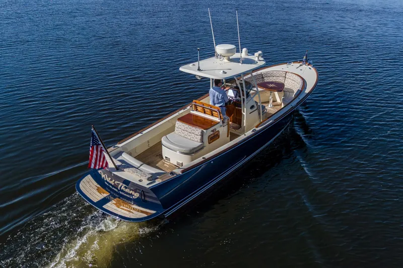 Slide: The Image of 2014 Hinckley Talaria 29C cruising on calm waters, featuring elegant design and American flag. - 5