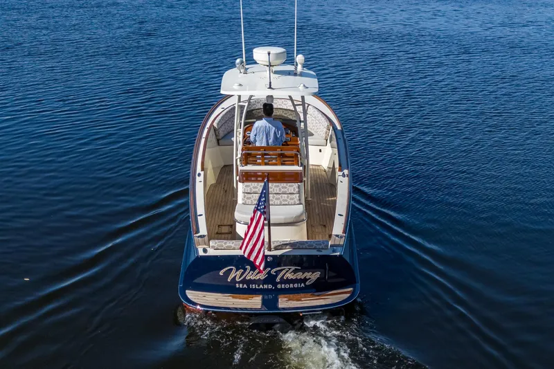 Slide: The Image of 2014 Hinckley Talaria 29C boat cruising on water, rear view with American flag. - 8