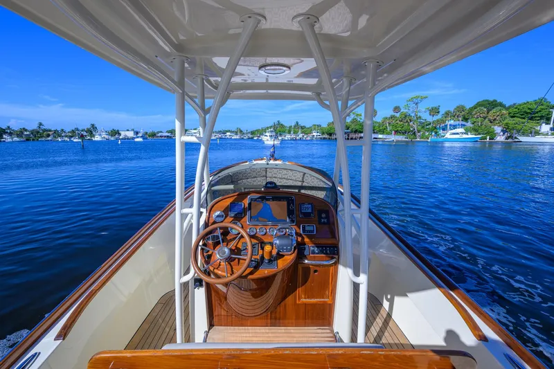 Slide: The Image of 2014 Hinckley Talaria 29C boat interior with wooden steering wheel, navigating on a sunny day. - 9