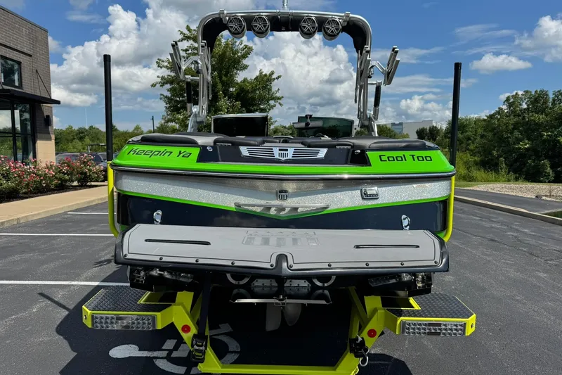 Slide: The Image of 2015 MasterCraft X30 boat with vibrant green accents, parked outdoors on a sunny day. - 4