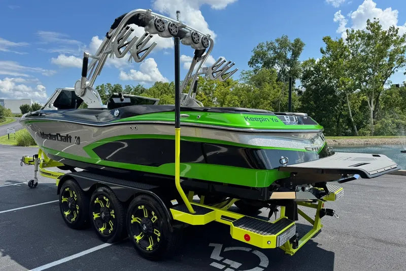 Slide: The Image of 2015 MasterCraft X30 boat on trailer, vibrant green and black design, parked near water. - 5