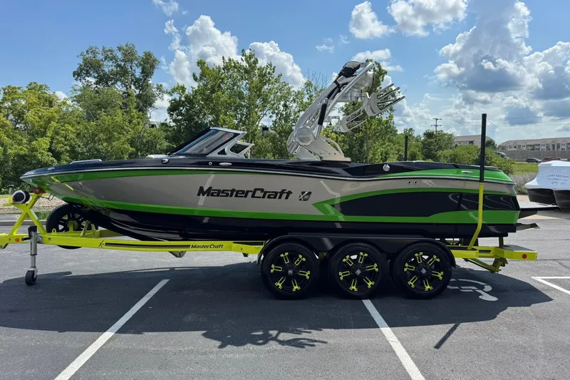 Slide: The Image of 2015 MasterCraft X30 boat on trailer, green and black design, parked outdoors. - 6