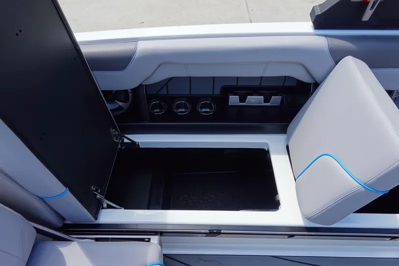Slide: The Image of 2021 Malibu Wakesetter 25 LSV interior storage compartment with open seat and cup holders. - 25