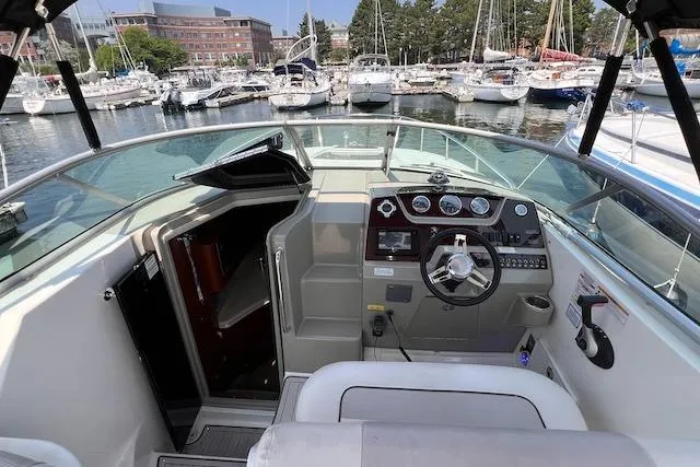 Slide: The Image of 2011 Sea Ray 280 Sundancer cockpit with steering wheel, gauges, and marina view. - 18