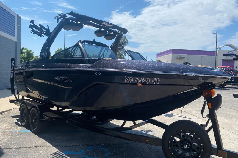 Slide: The Image of 2023 Tigé 23ZX boat on trailer, parked outdoors under a clear sky. - 37