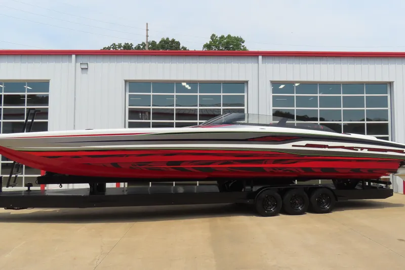 The Image of 2025 Skater 388 powerboat with red and black design on a trailer outside a garage. - 0