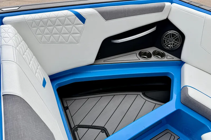 Slide: The Image of 2025 Nautique Super Air Nautique GS24 interior with blue accents, cup holders, and speaker. - 19