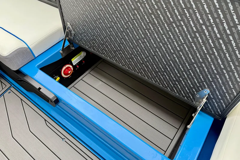 Slide: The Image of 2025 Nautique Super Air Nautique GS24 storage compartment with open lid and control panel. - 21