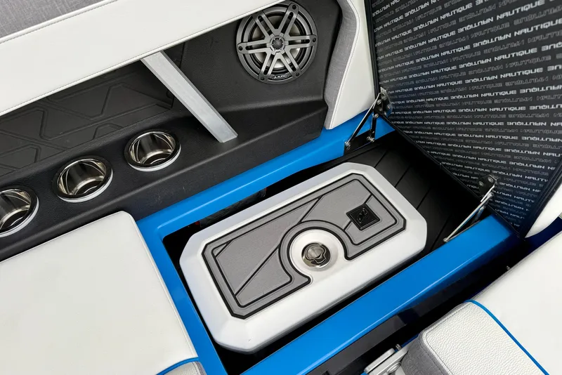 Slide: The Image of 2025 Nautique Super Air Nautique GS24 interior with speaker, cup holders, and storage compartment. - 23