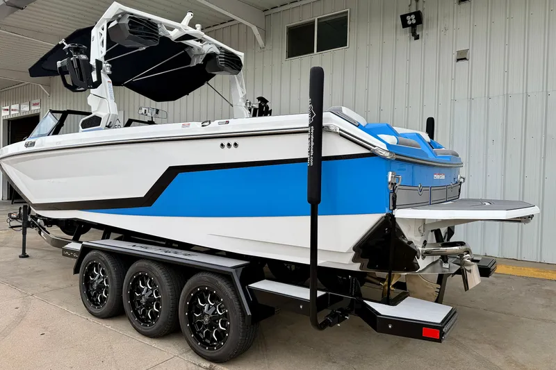 Slide: The Image of 2025 Nautique Super Air Nautique GS24 boat on a triple-axle trailer, blue and white design. - 3