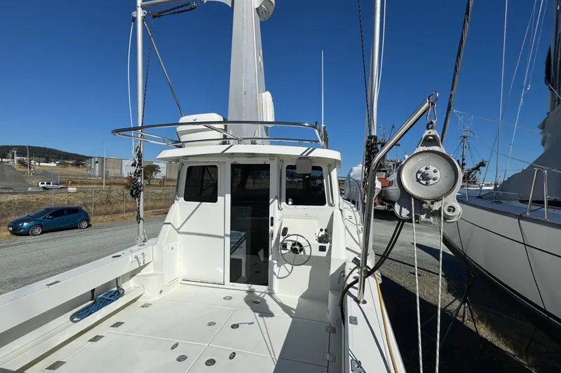 Slide: The Image of 2005 Ocean Sport Roamer 30 boat on land, showcasing deck and cabin area. - 13