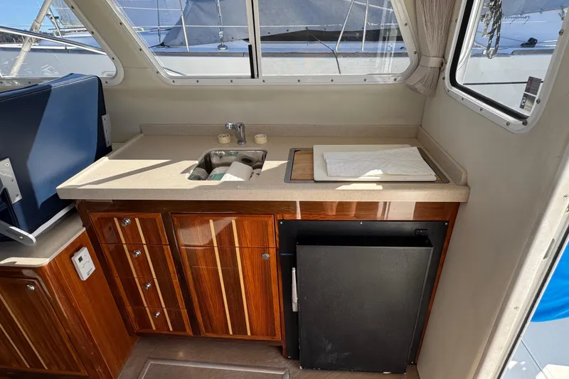 Slide: The Image of 2005 Ocean Sport Roamer 30 interior with kitchenette, sink, and wooden cabinetry. - 31