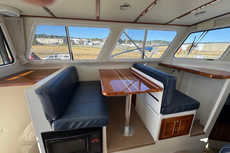 Slide: The Image of Interior of 2005 Ocean Sport Roamer 30 with blue seating and wooden table. - 34