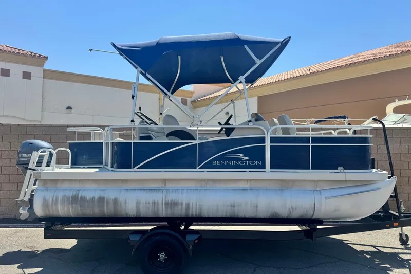 Slide: The Image of 2019 Bennington 188 SV pontoon boat with blue canopy on trailer. - 0