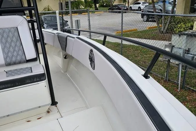 Slide: The Image of 1997 Fountain Sportfish 27 boat interior with seating and railing, parked near a fence. - 11