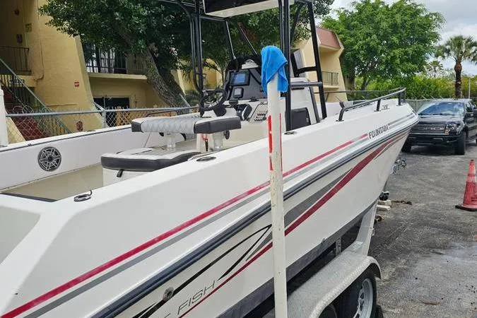 Slide: The Image of 1997 Fountain Sportfish 27 boat on trailer, parked outdoors near residential area. - 17