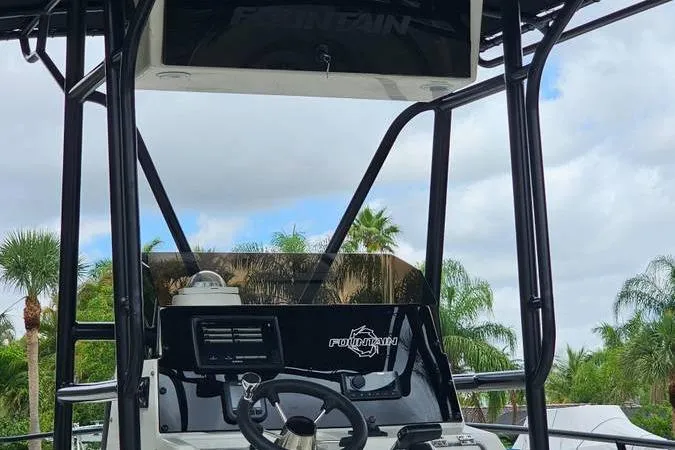 Slide: The Image of 1997 Fountain Sportfish 27 boat console with steering wheel, surrounded by palm trees. - 20